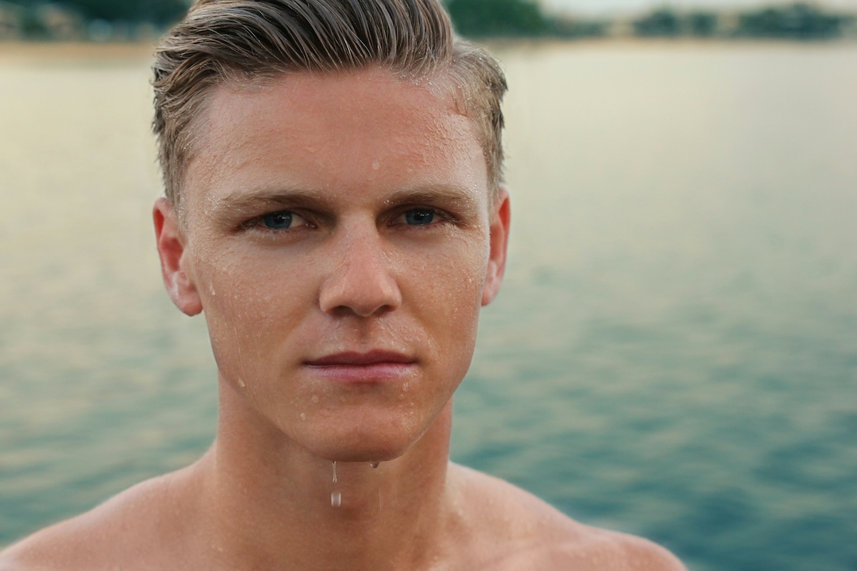 closeup of man with wet face standing by water